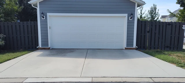 Clean concrete driveway after pressure washing in front of a detached garage in Pineville, NC.